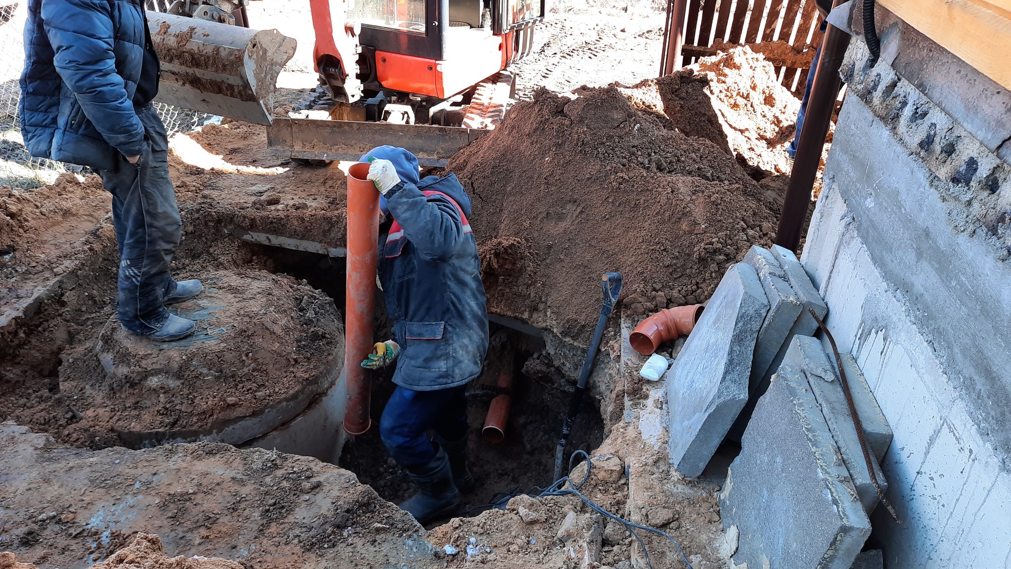 construction worker assembles sewer pipes into a sewage well